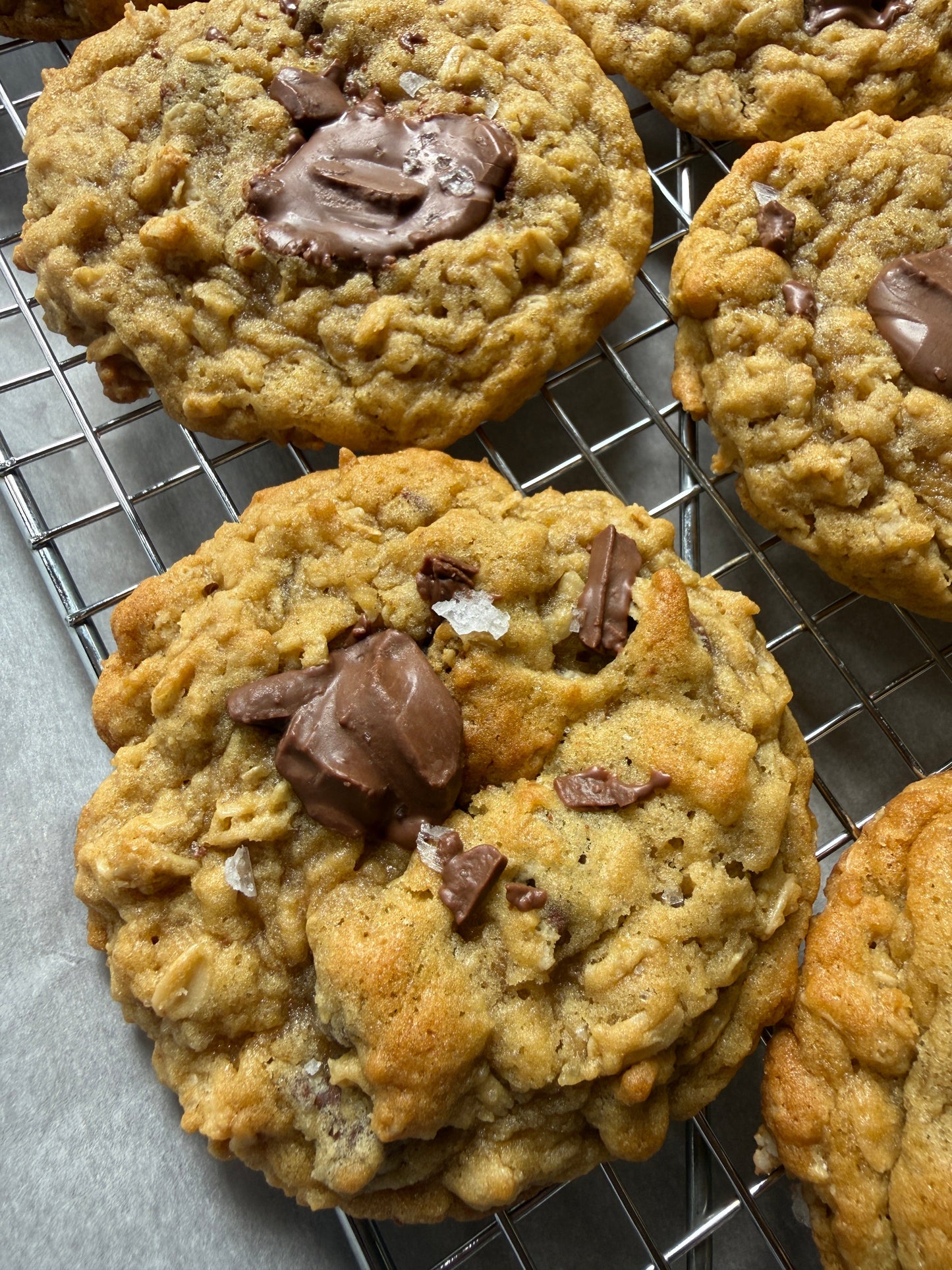 Chocolate chip cookies on a cooling rack with a gray surface underneath